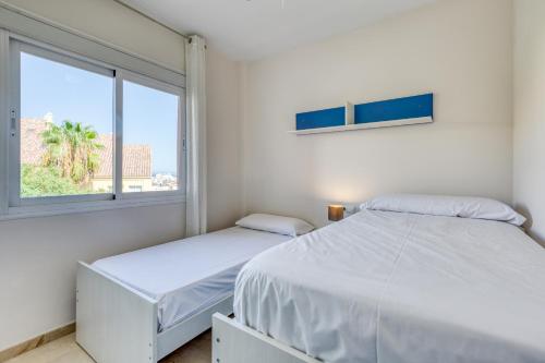 2 bedden in een witte kamer met een raam bij La Fragata Penthouse LF1 in Estepona