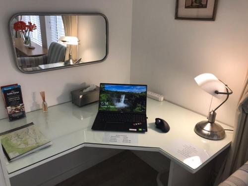 a laptop computer sitting on a desk with a mirror at Summer Place, Southern Cross Drive, Constantia, Cape Town in Cape Town