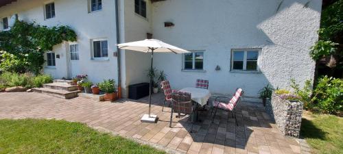 tavolo e sedie con ombrellone davanti casa di Ruhig gelegene Ferienwohnung mit großer Terrasse a Rotthalmünster