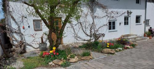 a house with a tree and flowers in front of it at Ruhig gelegene Ferienwohnung im Grünen mit Terrasse und kleinem Garten in Rotthalmünster