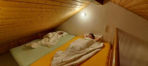 two people laying in beds in a attic at Ruhig gelegene Ferienwohnung im Grünen mit Terrasse und kleinem Garten in Rotthalmünster