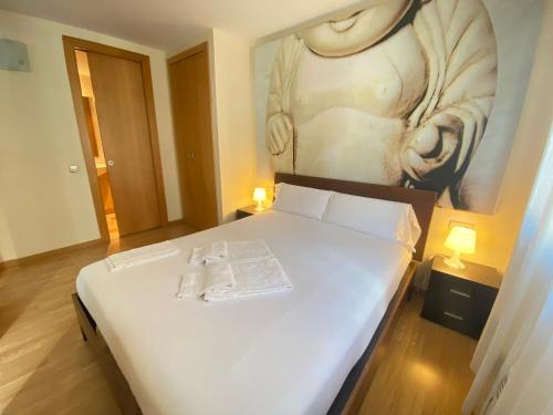 a bedroom with a white bed with a painting on the wall at P&C Sol Tarter in El Tarter