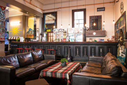 uma sala de estar com sofás de couro e um bar em Sundancer Backpackers Hostel em Fremantle