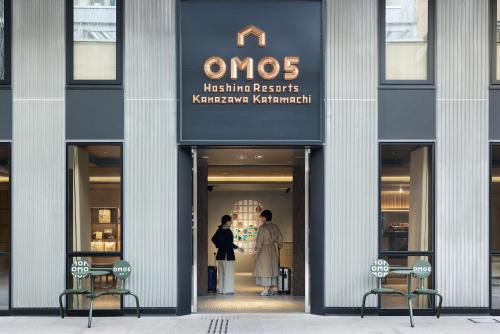 dos personas de pie en la puerta de una tienda en OMO5 Kanazawa Katamachi by Hoshino Resorts, en Kanazawa