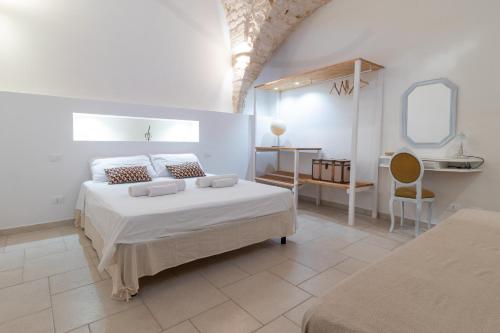 een witte slaapkamer met een bed en een spiegel bij Casa Maestra in Ceglie Messapica