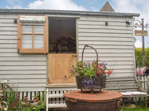 a tiny house with a window and a basket of flowers at Shepards Hut in Frampton on Severn