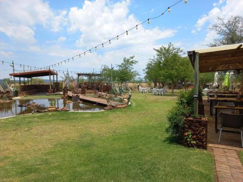 un jardín con mesa, sillas y un estanque en Nyani Lodge Dinokeng, en Pretoria