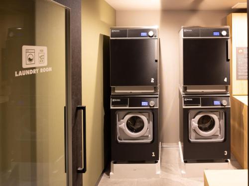 a laundry room with two washing machines and a tv at OMO5 Kanazawa Katamachi by Hoshino Resorts in Kanazawa