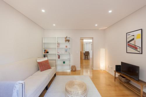 un salon avec un canapé blanc et une télévision dans l'établissement FLH Gulbenkian Apartment with Balcony, à Lisbonne