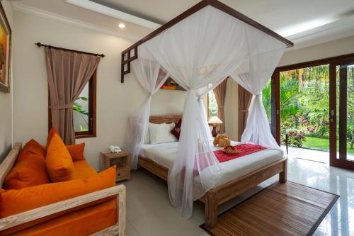 a bedroom with two beds and a canopy bed at Kiskenda Cottages & Restaurant in Ubud