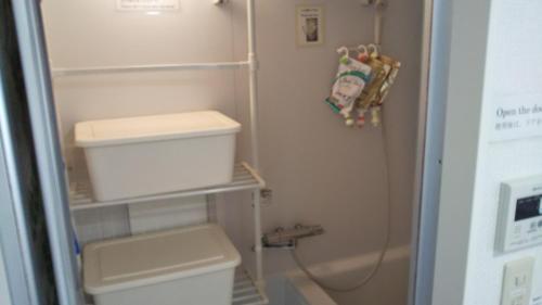 La petite salle de bains est pourvue d'une douche et de toilettes. dans l'établissement ゲストハウス小富士, à Ōita