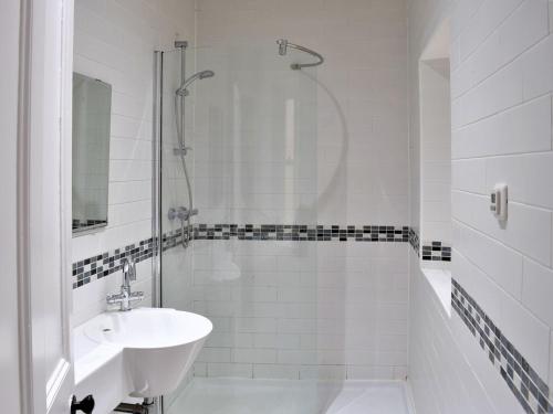 a white bathroom with a sink and a shower at Sanderling End in Lowick