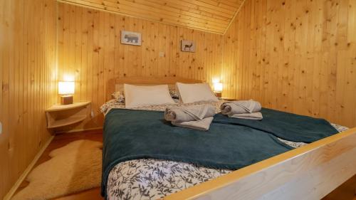 a bed in a wooden room with two towels on it at Gorska Vila in Mrkopalj