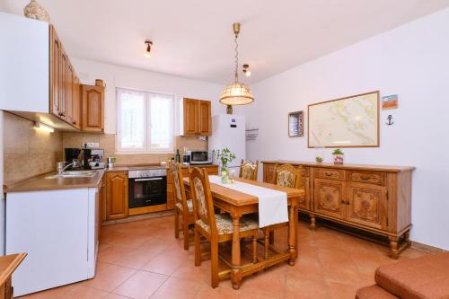 a kitchen with a wooden table and a white refrigerator at Apartments Antares in Mali Lošinj