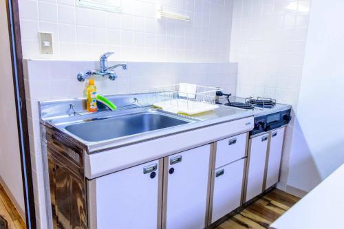 a kitchen with a sink and a stove at Hakuba Inn Bloom in Hakuba