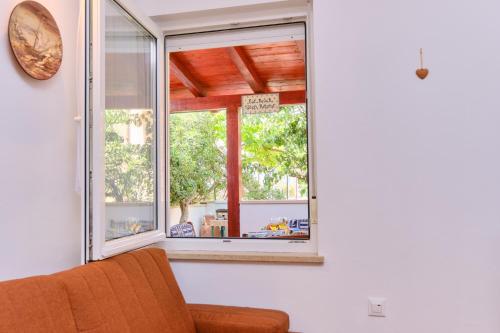 a living room with a window and a chair at Apartments Antares in Mali Lošinj