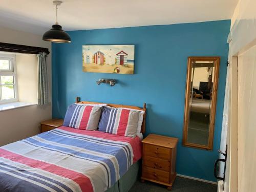 niebieska sypialnia z łóżkiem i lustrem w obiekcie The Hayloft w mieście Bude