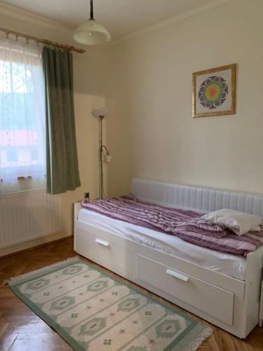 Schlafzimmer mit einem Bett, einem Fenster und einem Teppich in der Unterkunft Gyöngyvirág Vendégház in Noszvaj