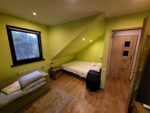 a bedroom with green walls and a bed and a window at Zaciszny dom z plażą nad jeziorem Chańcza in Raków