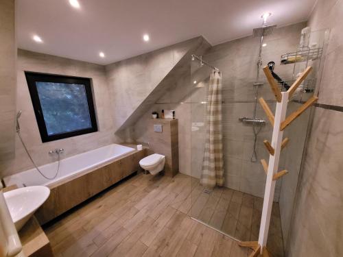 a bathroom with a tub and a sink and a shower at Zaciszny dom z plażą nad jeziorem Chańcza in Raków