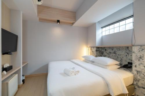 a bedroom with a large white bed with a window at Metz Pratunam in Bangkok