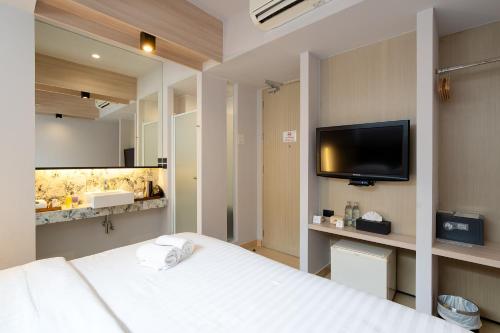 a bedroom with a bed and a flat screen tv at Metz Pratunam in Bangkok
