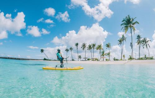 a person on a paddle board in the water on a beach at The Bilimbi Guesthouse & Inn in Huraa