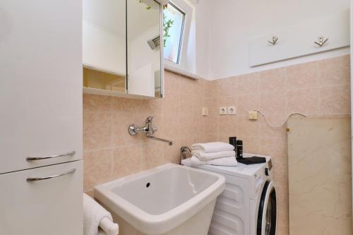a bathroom with a sink and a washing machine at Apartments Antares in Mali Lošinj