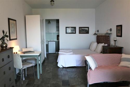 a bedroom with a white bed and a desk and a chair at Sea view studio in Batsi