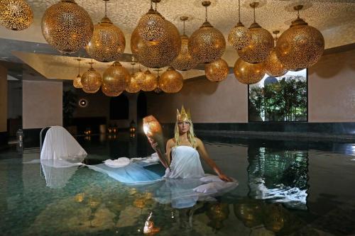 Eine Frau in einem Kleid, die im Pool sitzt. in der Unterkunft Hotel Jadali & Spa in Marrakesch