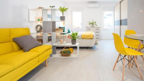 een woonkamer met een gele bank en een tafel bij Acogedora casa de invitados con piscina compartida in Toledo