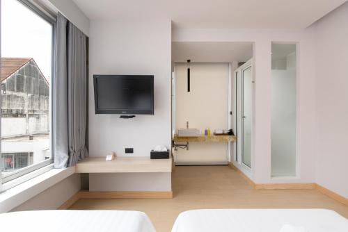 a living room with a tv on a white wall at Metz Pratunam in Bangkok