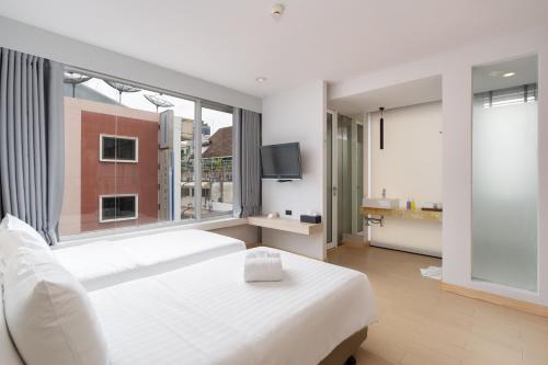 a bedroom with a white bed and a large window at Metz Pratunam in Bangkok