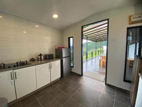 a kitchen with a refrigerator and a door to a patio at Bayu Senja Lodge in Kundasang