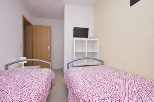 a bedroom with two beds and a tv on a shelf at Having in Ostseebad Sellin