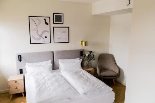 a bedroom with a white bed and a chair at Bob W Peterhof in Freising