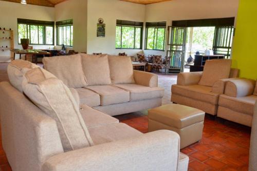 a living room with couches and tables and windows at Gorilla Hills Eco-lodge in Kisoro