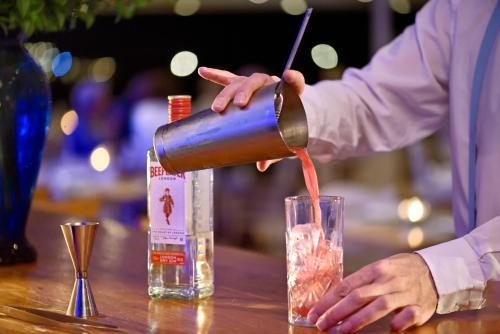 a person pouring a drink into a glass on a table at Petinos Hotel in Platis Yialos Mykonos