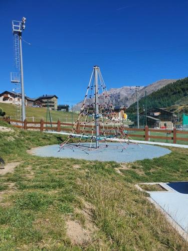 a playground in a field next to a fence at Pianeta Oro Chalet Allegra in Livigno