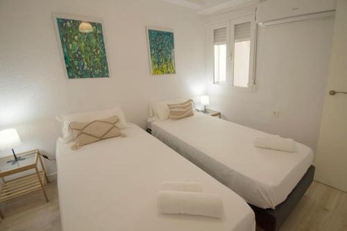 2 camas en una habitación con paredes blancas en Apartamentos Centro Granada, en Granada