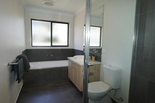 a bathroom with a toilet and a sink and a shower at Captains Edge- Brand New 3 bedroom spacious home, private afresco & yard central to Paynesville CBD in Paynesville