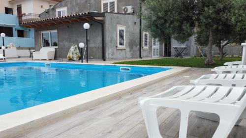 Debel house في مارينا دي راغوزا: مسبح وكراسي بيضاء بجوار منزل