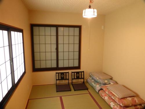 a room with two beds in a room with windows at Guesthouse Engawa in Kyoto