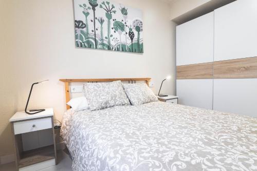 a bedroom with a large bed and two lamps at Apartamento chile playa in Gijón