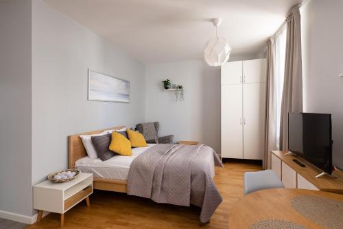 a white bedroom with a bed and a tv at Residential Barona Apartments in Riga Centre in Rīga