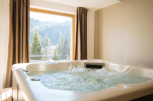 a bath tub filled with water in front of a window at Hotel Rajska dolina Jahorina in Jahorina