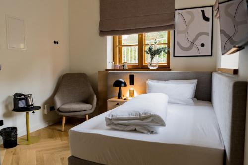 a bedroom with a bed and a chair and a window at Bob W Peterhof in Freising