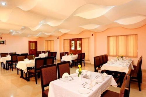 un restaurante con mesas y sillas con mantel blanco en BROAD BEAN Chakkarakkal, en Chakkarakkal