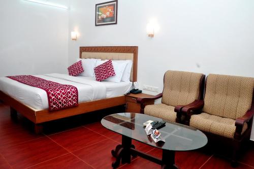 a hotel room with a bed and two chairs and a table at BROAD BEAN Chakkarakkal in Chakkarakkal