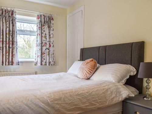 a bedroom with a bed with white sheets and a window at Hollywell Cottages in Clifton